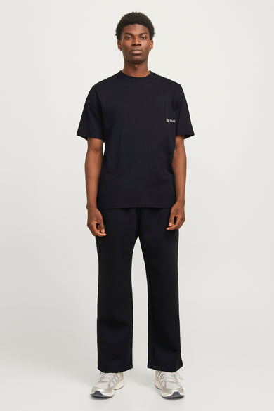 T-shirt noir à manches courtes de CORE BY JACK & JONES, associé à un pantalon noir et des baskets blanches.