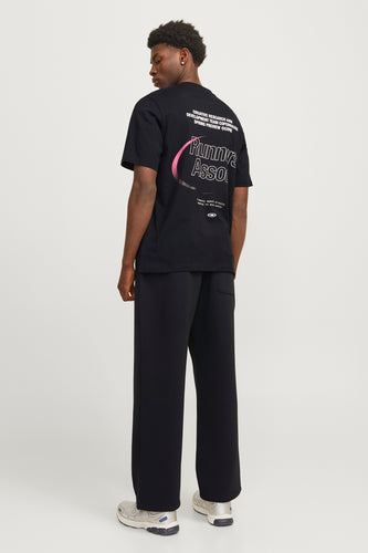 Man, zwarte T-shirt en joggingbroek, witte achtergrond.