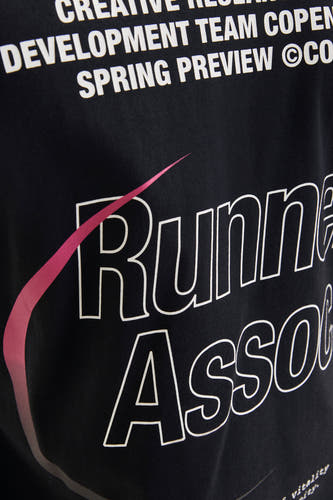 T-shirt noir à manches courtes de CORE BY JACK & JONES, avec une impression blanche 'Runner Asso' et un détail rose.