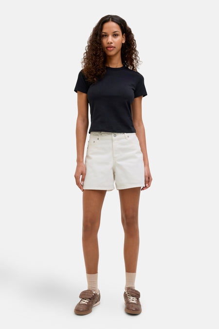 Short blanc de JJXX, associé à un T-shirt noir et des baskets brunes.