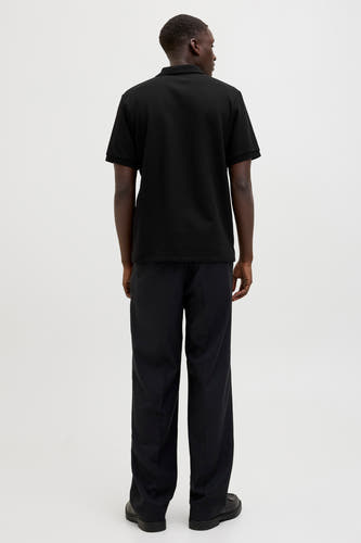 Polo noir à manches courtes de CORE BY JACK & JONES, vu de dos, avec un pantalon noir et des chaussures noires.