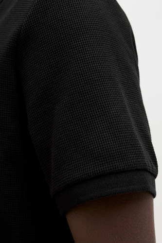 Polo noir à manches courtes de CORE BY JACK & JONES, avec une structure à carreaux et une peau foncée.