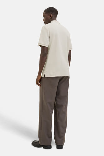 Polo beige à manches courtes de CORE BY JACK & JONES, avec une subtile texture, associé à un pantalon brun large et des chaussures noires.