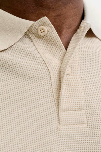 Polo beige à manches courtes de CORE BY JACK & JONES, avec structure gaufrée, boutons de couleur crème et patte de boutonnage partiellement ouverte.