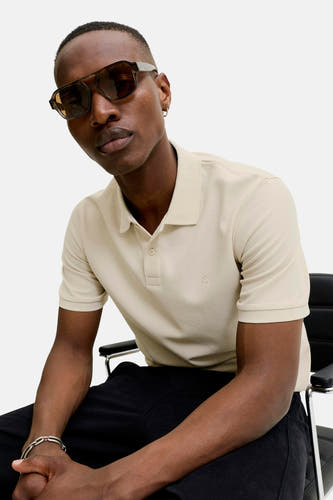 Beige polo met korte mouwen van CORE BY JACK & JONES, met wafelstructuur en geborduurd logo, gedragen door een model.