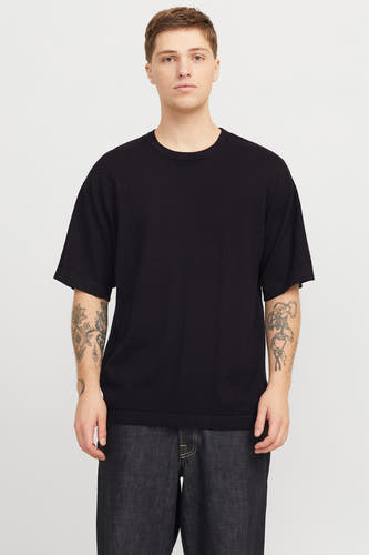 T-shirt noir à manches courtes de PREMIUM by JACK & JONES, avec des tatouages sur les deux bras, associé à un jean foncé.
