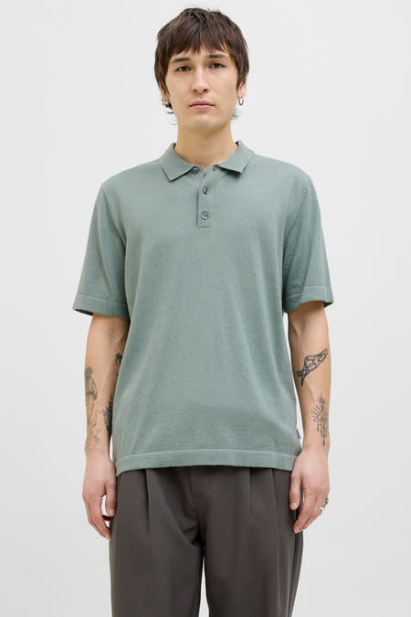 Polo vert de mantes man courts PRE PRE by by by by & J, avec JACK boutons et porté avec un pantalon gris.