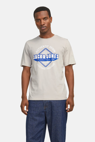 T-shirt écru à manches courtes d'ORIGINALS BY JACK & JONES, avec un logo bleu et blanc sur la poitrine, associé à un pantalon bleu marine.