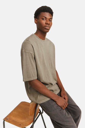 T-shirt vert de mantes courtes CORE BY JACK & JONES, porté avec un jean gris et assis sur une chaise en bois.