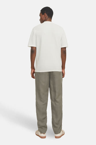 Pull blanc de CORE BY JACK & JONES, à manches courtes et à la texture subtile, porté avec un pantalon en lin vert olive et des baskets couleur crème.