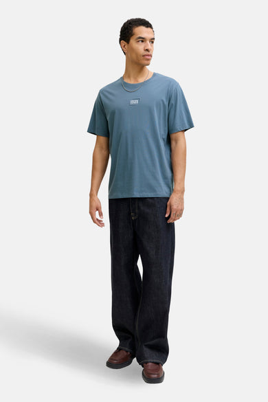 Blauw T-shirt met korte mouwen van CORE by JACK & JONES, met een logo op de borst, gecombineerd met donkere jeans en bruine schoenen.