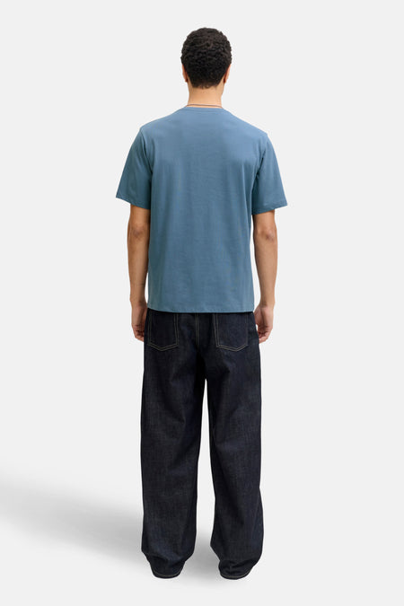 T-shirt bleu à manches courtes de CORE BY JACK & JONES, porté avec des jeans foncés larges.