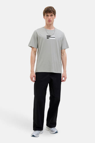 T-shirt gris à manches courtes de CORE par JACK & JONES, avec une chaîne d'argent et un pantalon noir.