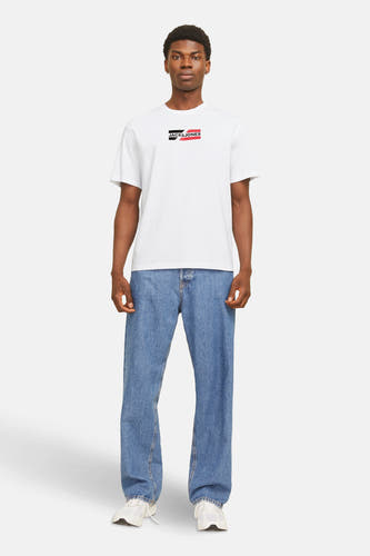 T-shirt blanc à manches courtes de CORE par JACK & JONES, porté avec un jean bleu et des baskets blanches.