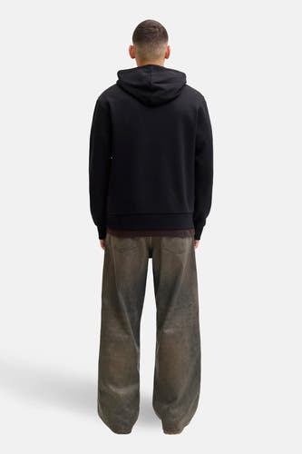 Pull-over noir avec capuche de CORE BY JACK & JONES, associé à un t-shirt marron et des jeans larges.