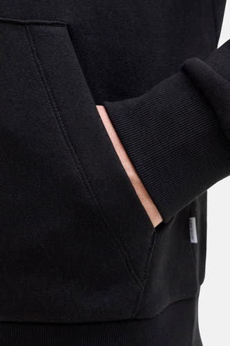 Gilet noir à capuche de CORE par JACK & JONES, avec une main dans la poche et des manches côtelées.