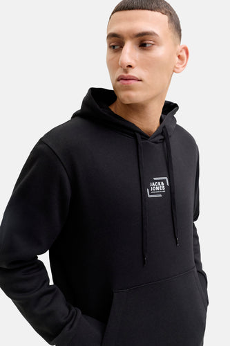 Een jonge man draagt een zwarte hoodie met het Jack & Jones-logo.