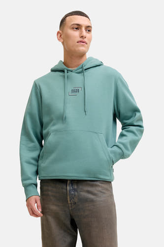 Pull-over bleu avec capuche de CORE BY JACK & JONES, avec cordon de serrage, une poche et porté avec un pantalon et des chaussures.