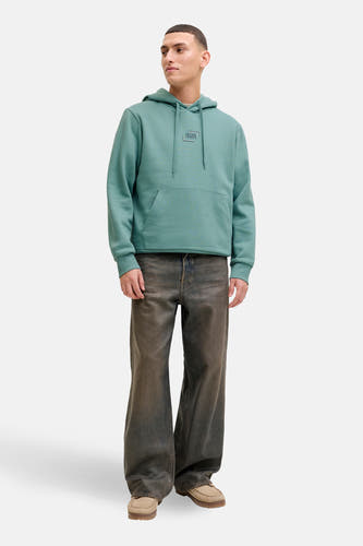 Blauwe sweater met kap van CORE BY JACK & JONES, met trekkoorden, een zak en gedragen met een broek en schoenen.