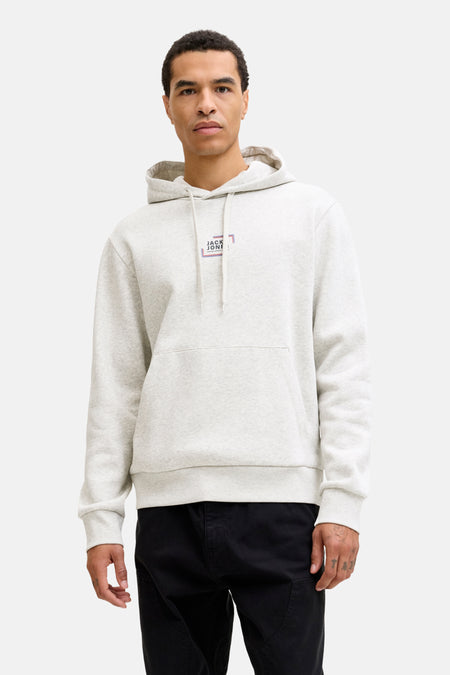 Een man draagt een grijze hoodie met zwarte broek.