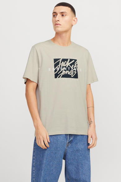 T-shirt beige à manches courtes d'ORIGINALS BY JACK & JONES, avec une impression graphique et porté avec des jeans bleus.