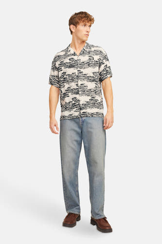 Chemise noire à manches courtes de CORE BY JACK & JONES, avec un motif ondulé, portée avec des jeans et des chaussures marrons.