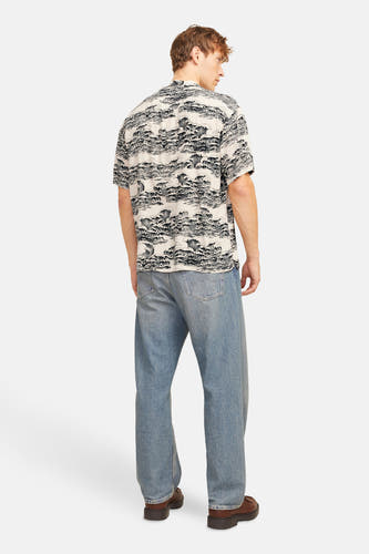 Chemise noire à manches courtes de CORE BY JACK & JONES, avec un motif ondulé, associée à des jeans bleus et des chaussures marrons.