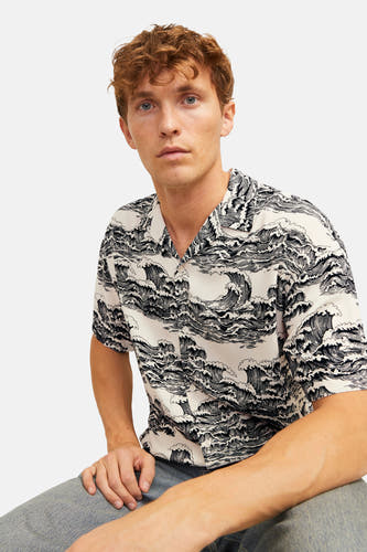 Chemise noire à manches courtes de CORE BY JACK & JONES, avec un motif ondulé et des jeans visibles.