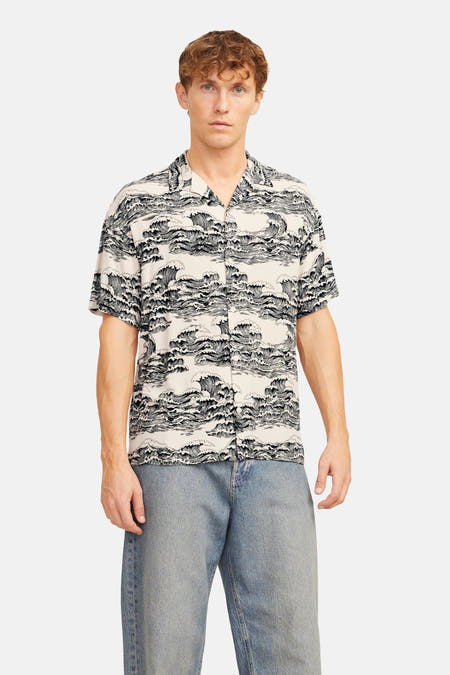 T-shirt noir à manches courtes de CORE BY JACK & JONES, avec un imprimé d'ondulations, porté avec un jean bleu.