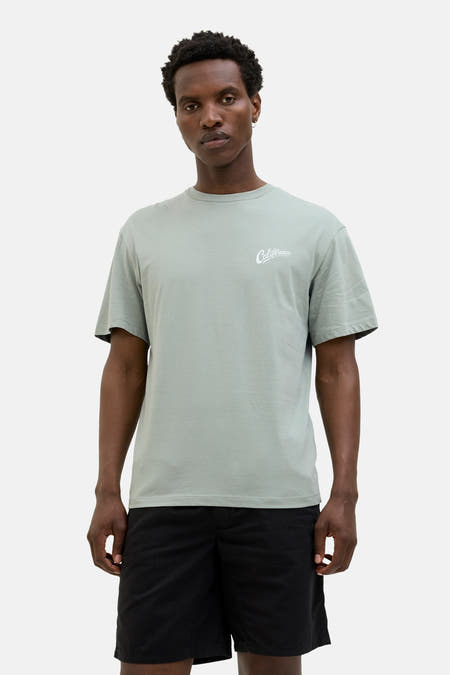 T-shirt vert de mantes courtes courSSSSS & J J,éééé avec shorts noirs et des chaussettes blanches.