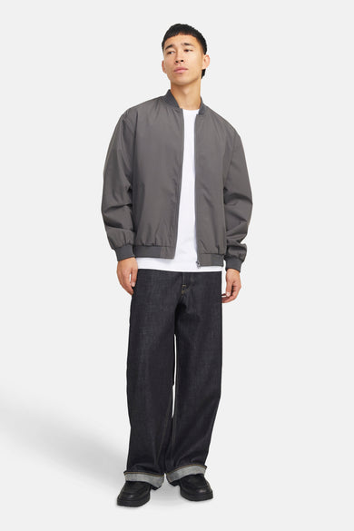 Manteau gris court de PREMIUM par JACK & JONES, porté sur un T-shirt blanc avec des jeans foncés larges et des chaussures noires.