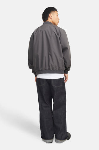 Manteau gris court de PREMIUM par JACK & JONES, porté avec un T-shirt blanc et des jeans larges foncés.