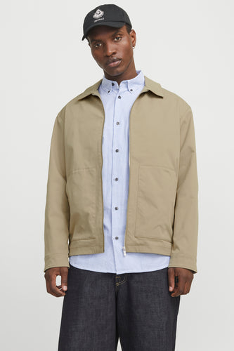 Mannequin met jas, overhemd, jeans en pet.