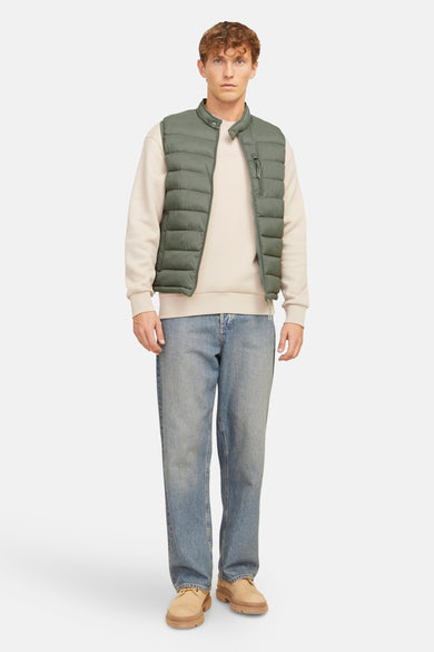 Gilet en kaki de PREMIUM BLUE par JACK & JONES, porté sur un pull beige et des jeans bleus.