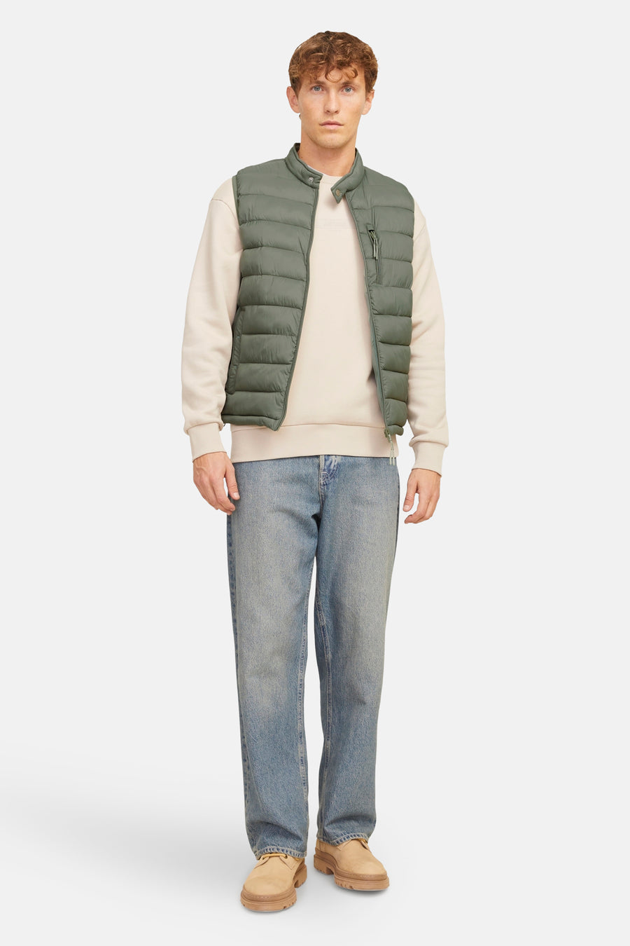 Gilet en kaki de PREMIUM BLUE par JACK & JONES, porté sur un pull beige et des jeans bleus.