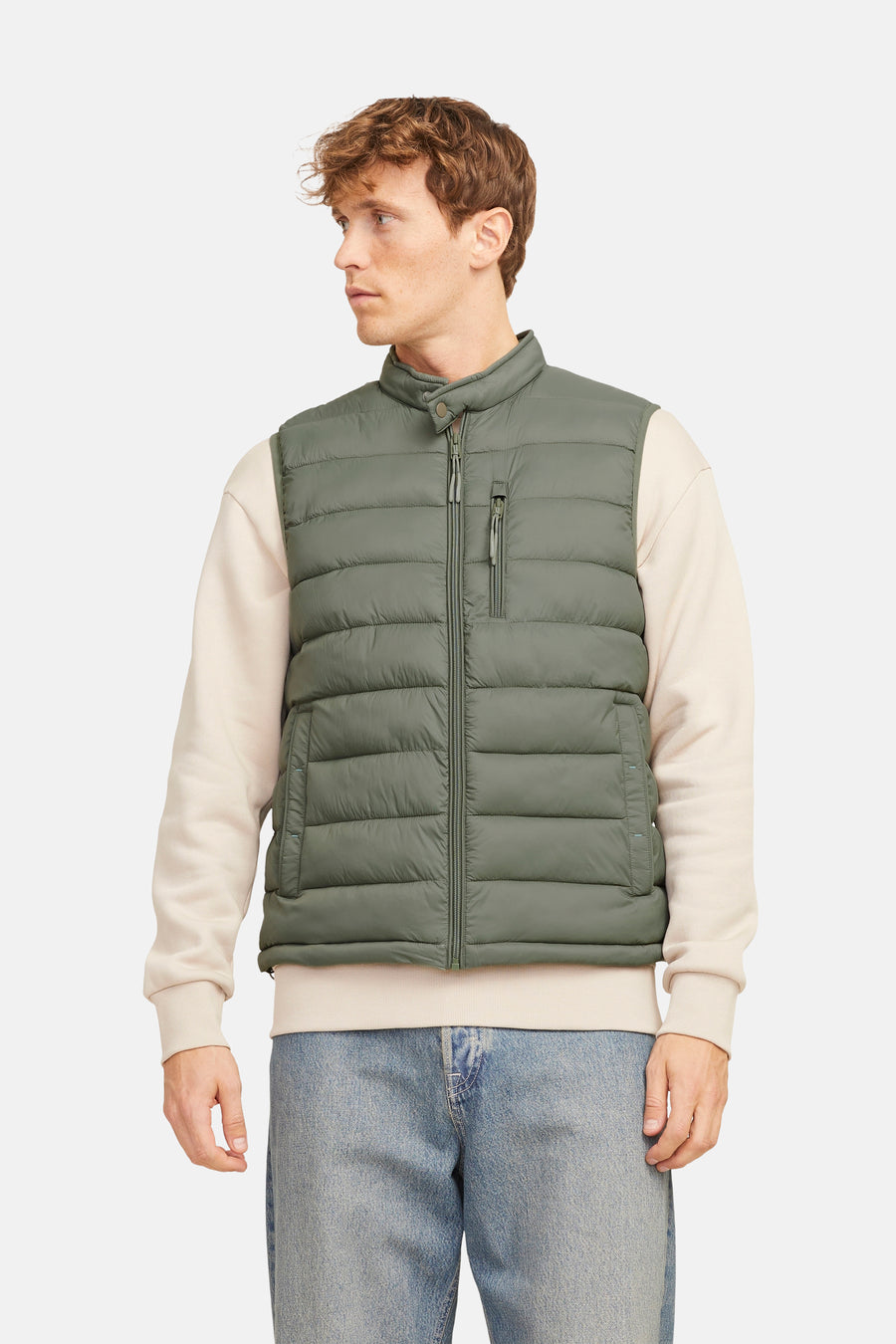 Gilet bodywarmer de PREMIUM BLUE par JACK & JONES, porté sur un pull beige et des jeans bleus.