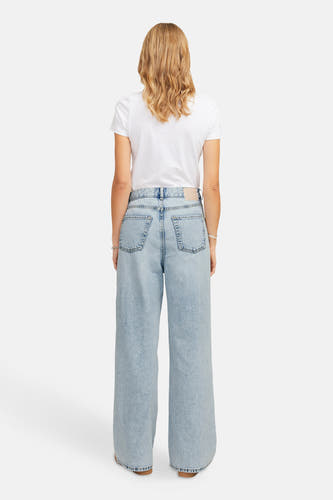 Jean bleu clair large de JJXX, vu de l'arrière avec un T-shirt blanc et des chaussures marrons.
