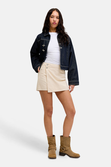 Ecru skort van JJXX, gecombineerd met een denim jack en bruine laarzen.
