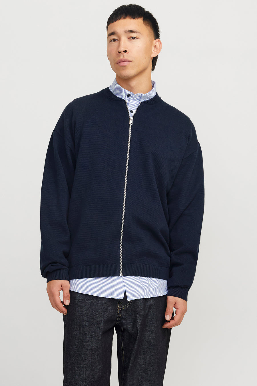 Veste bleue d'ORIGINALS BY JACK & JONES, portée sur un chemisier rayé et un pantalon de denim foncé.