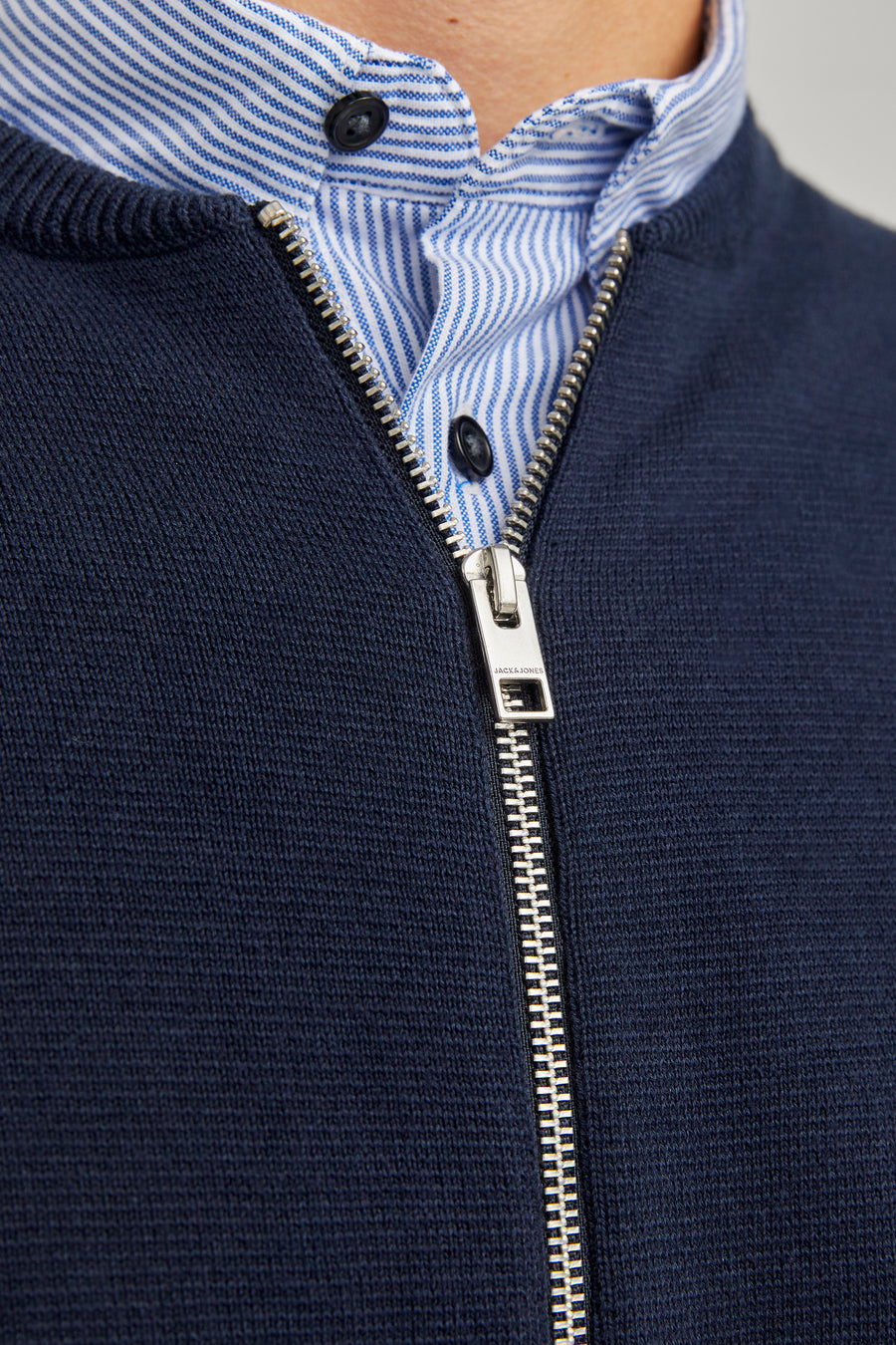 Veste bleue d'ORIGINALS BY JACK & JONES avec fermeture à glissière argentée sur un chemisier rayé.