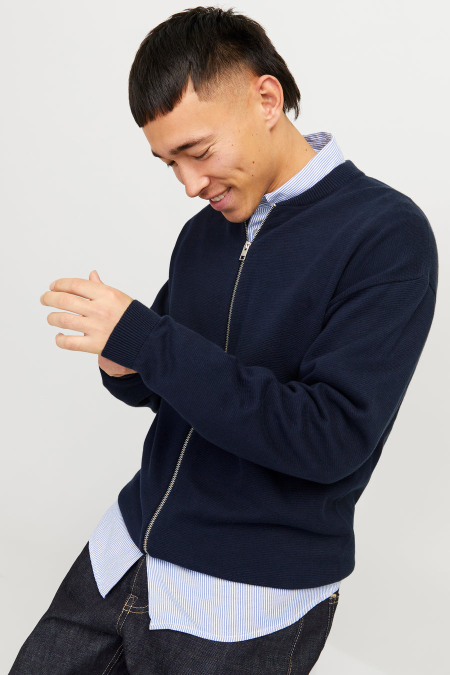 Veste bleue d'ORIGINALS BY JACK & JONES, à longues manches, portée sur un chemisier rayé et des jeans foncés.