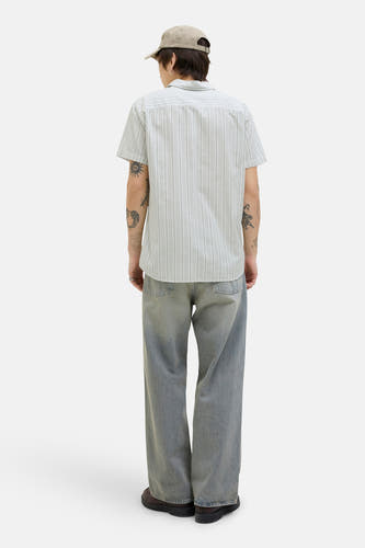Chemise verte à manches courtes de PREMIUM BLUE par JACK & JONES, avec des rayures verticales et portée avec des jeans et un chapeau.