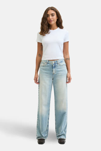 Wijdvallende jeans van lichtblauw denim van JJXX, gecombineerd met een wit T-shirt en zwarte schoenen.
