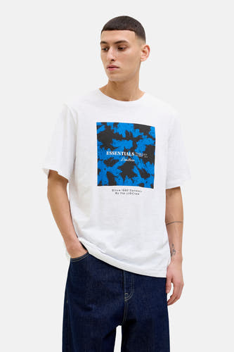 T-shirt blanc à manches courtes de CORE BY JACK & JONES, avec un motif bleu-noir sur l'avant, porté avec des jeans foncés.