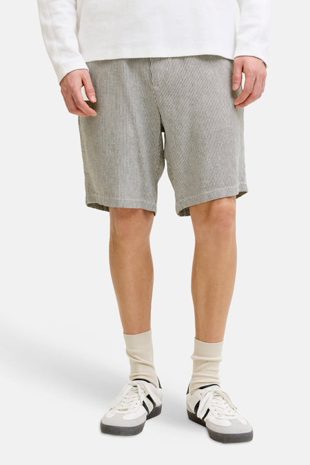 Short rayé kaki de JACK & JONES JEANS INTELLIGENCE, porté avec un haut blanc, des chaussettes crème et des baskets blanches.