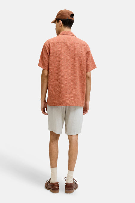 Short beige de JACK & JONES JEANS INTELLIGENCE, vu de dos sur un homme avec une chemise à motifs orange et des chaussures bateau marron.