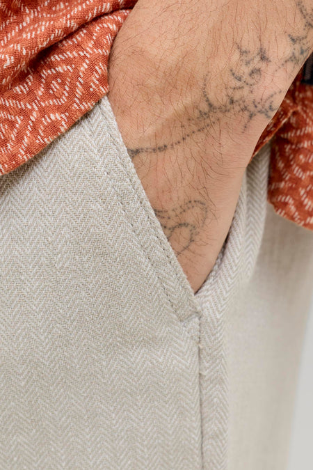 Short beige en linon à motif chevrons de JACK & JONES JEANS INTELLIGENCE, avec main dans la poche latérale et chemise orange.