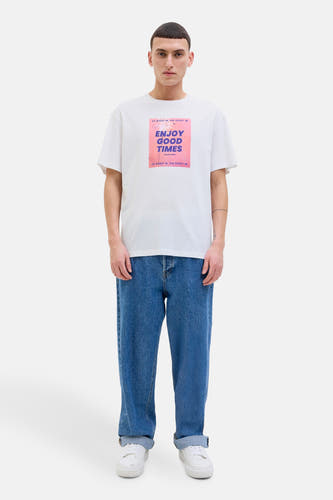 T-shirt blanc à manches courtes d'ORIGINALS BY JACK & JONES, avec un imprimé sur la partie avant, associé à des jeans bleus et des chaussures blanches.