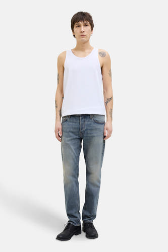 Jean tapered bleu denim mid JACK & JONES JEANS INTELLIGENCE, porté avec un tank-top blanc et des chaussures noires.