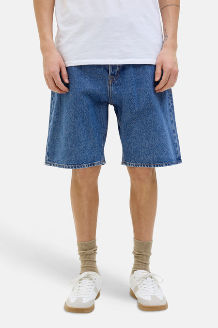 Short en jean bleu denim de JACK & JONES JEANS INTELLIGENCE coupe ample, stylé avec un t-shirt blanc, des chaussettes beiges et des baskets blanches.